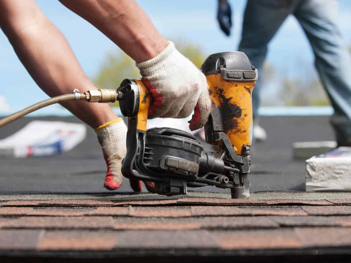 Roofer installing shingles on a suburban home